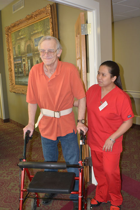 A resident assisted by staff in a hallway