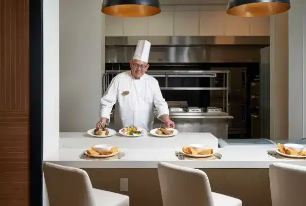 Chef presenting beautifully plated meals in a kitchen.