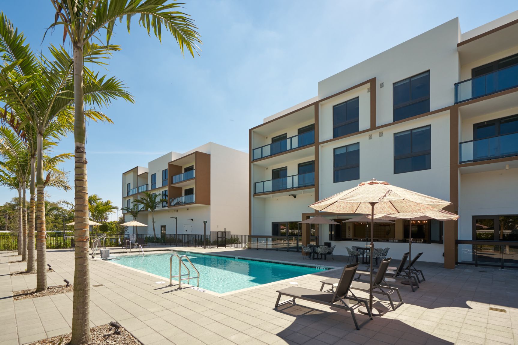 Outdoor pool area with lounge chairs and umbrellas.