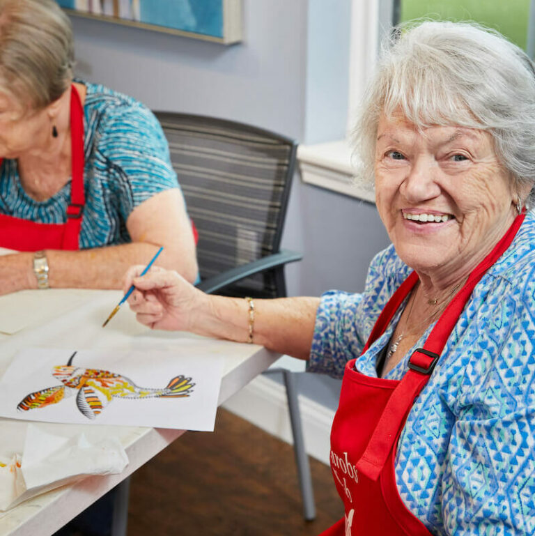 Residents engaged in a painting activity with smiles