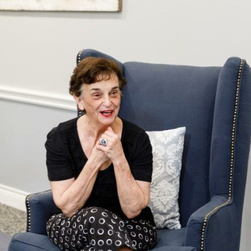 Resident smiling in a comfortable chair in a lounge area