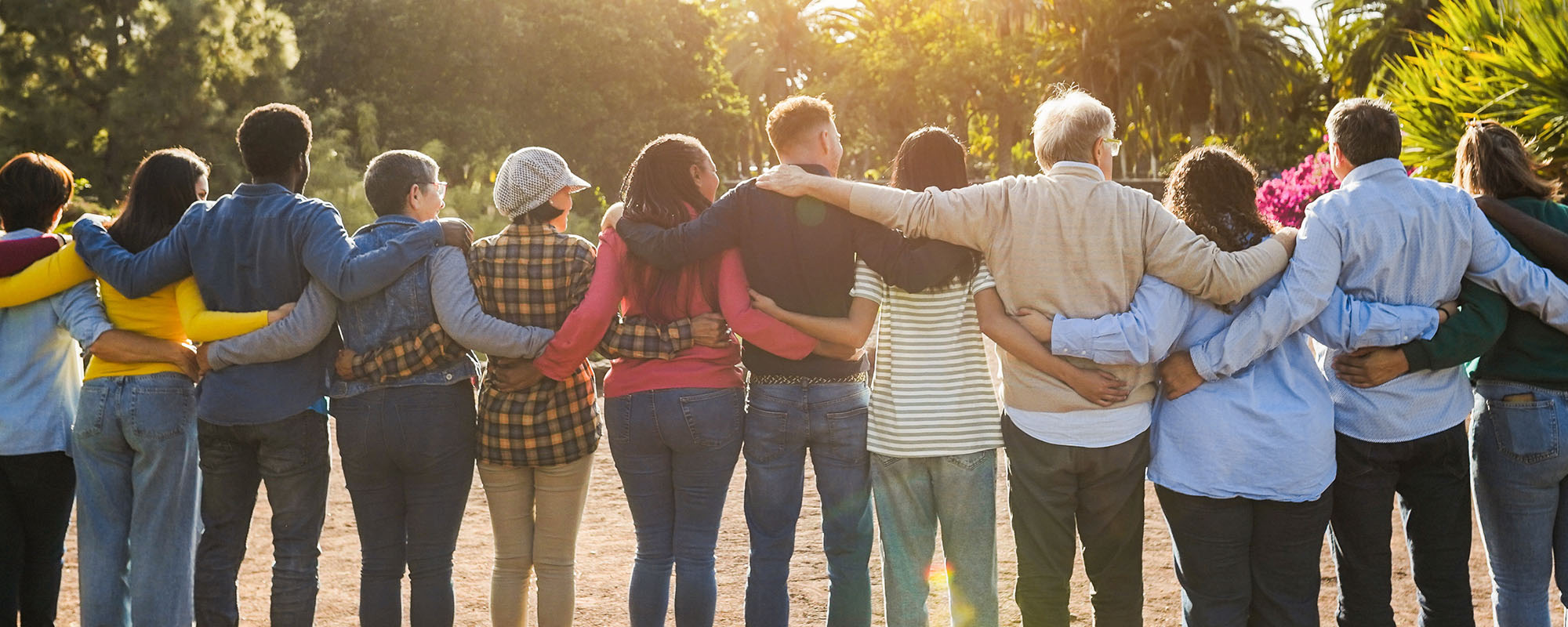 Group of diverse individuals hugging each other outdoors