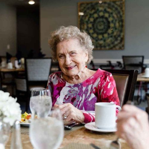 A smiling resident enjoying a meal in a dining room