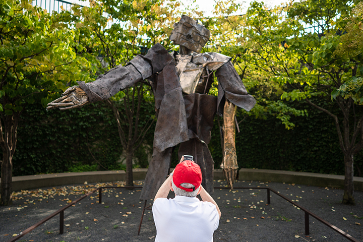 A resident photographing a sculpture in a garden