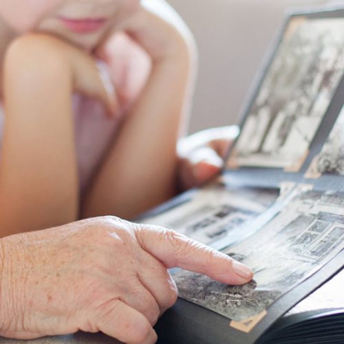 An older adult showing a photo album to a child.