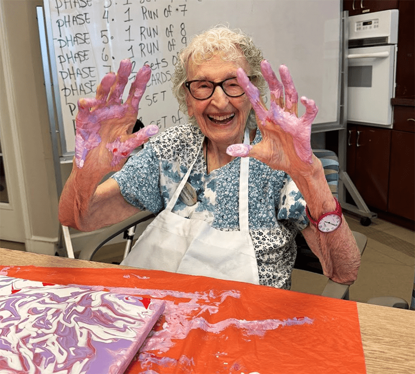 Resident enjoying a painting activity with colorful hands