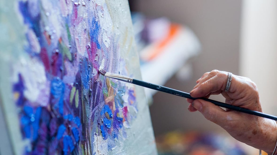 A resident painting on canvas in a bright art space