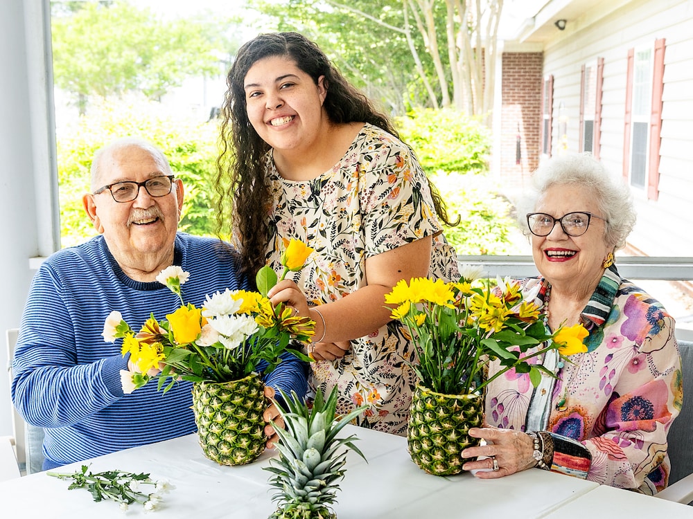 Residents and staff creating flower arrangements outdoors