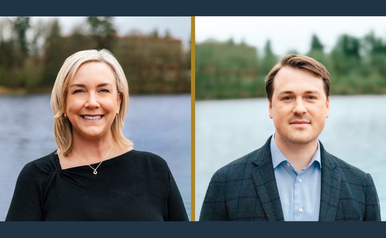 Two staff members posing outdoors by a lake