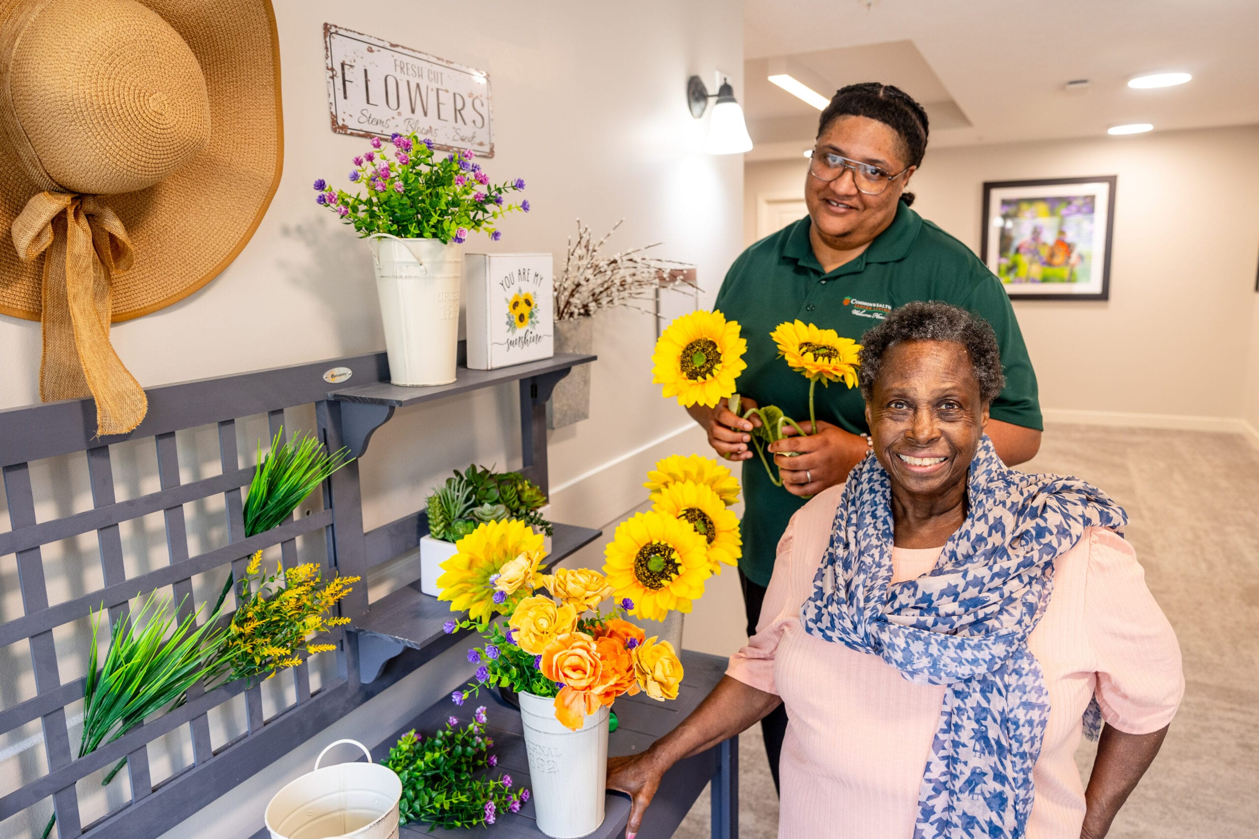 Resident and staff member arranging flowers in the common area