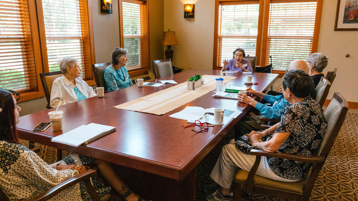 Residents and staff engaging in a meeting around a table