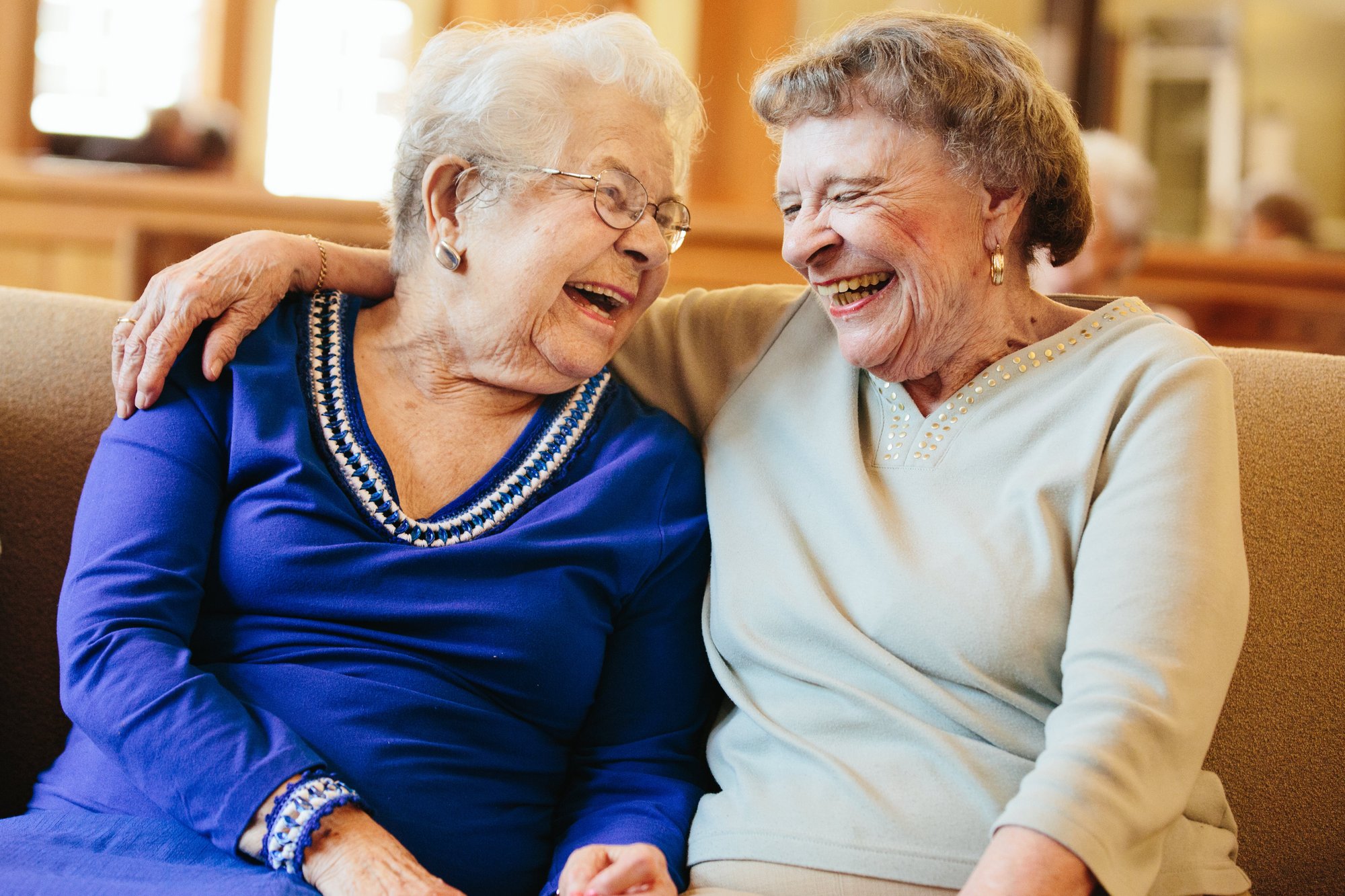 Two elderly women laughing together in a cozy setting