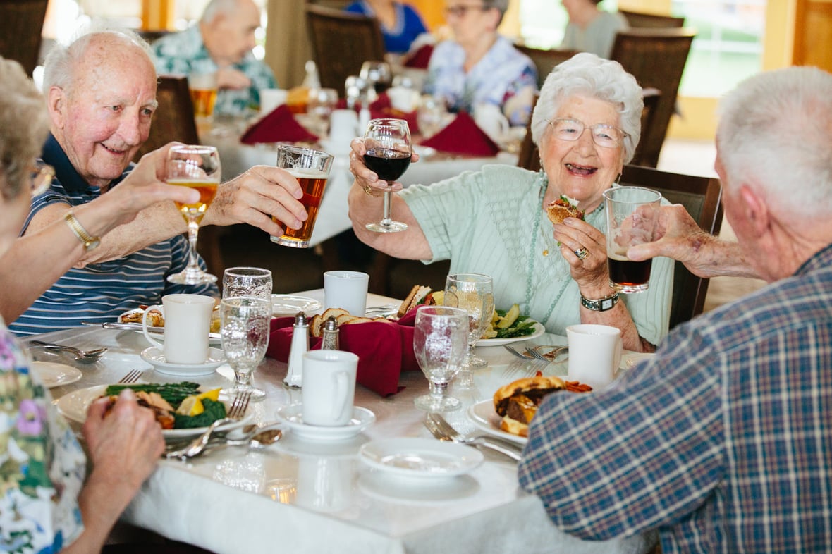 Residents enjoying a meal and toasting at a dining table