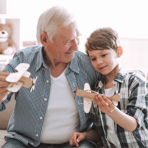 Grandfather and grandson playing with wooden airplanes