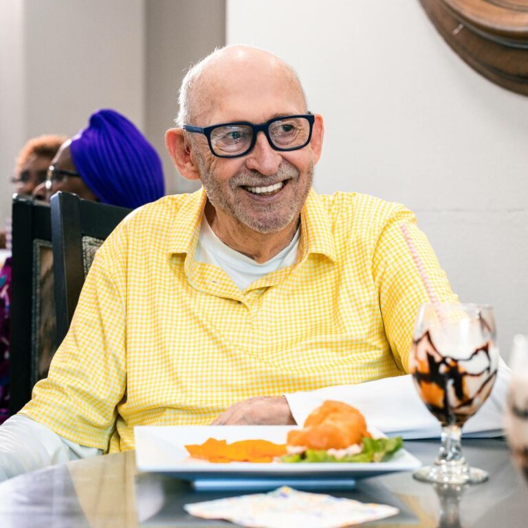 A smiling resident enjoying a meal in a dining area