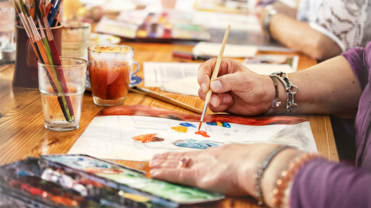 Residents participating in a painting activity at a shared table