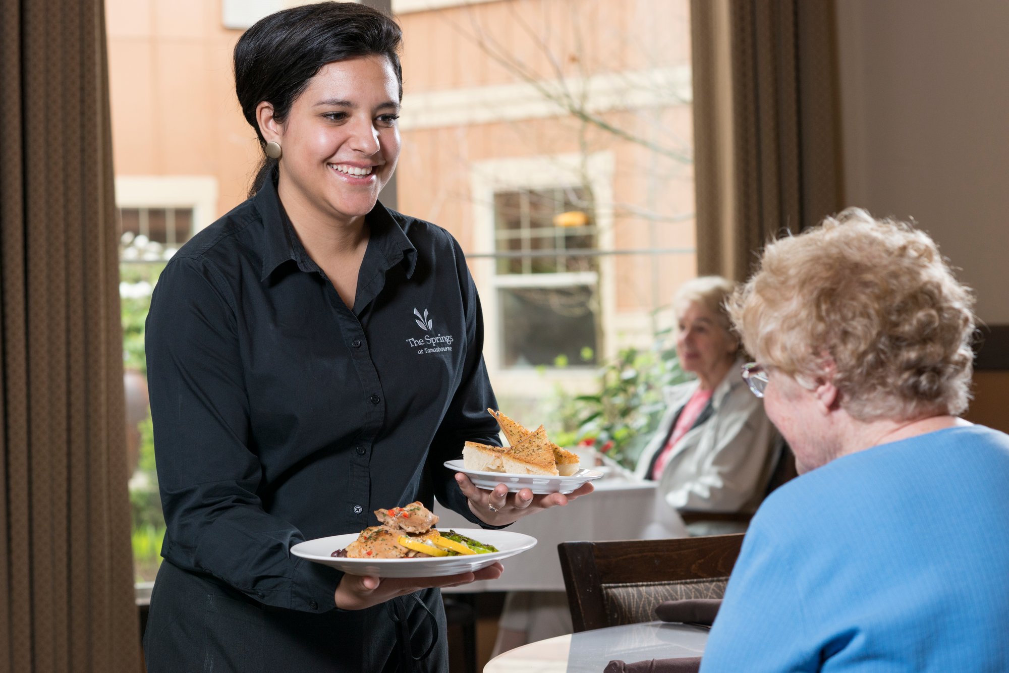 Staff serving food to a resident in the dining area