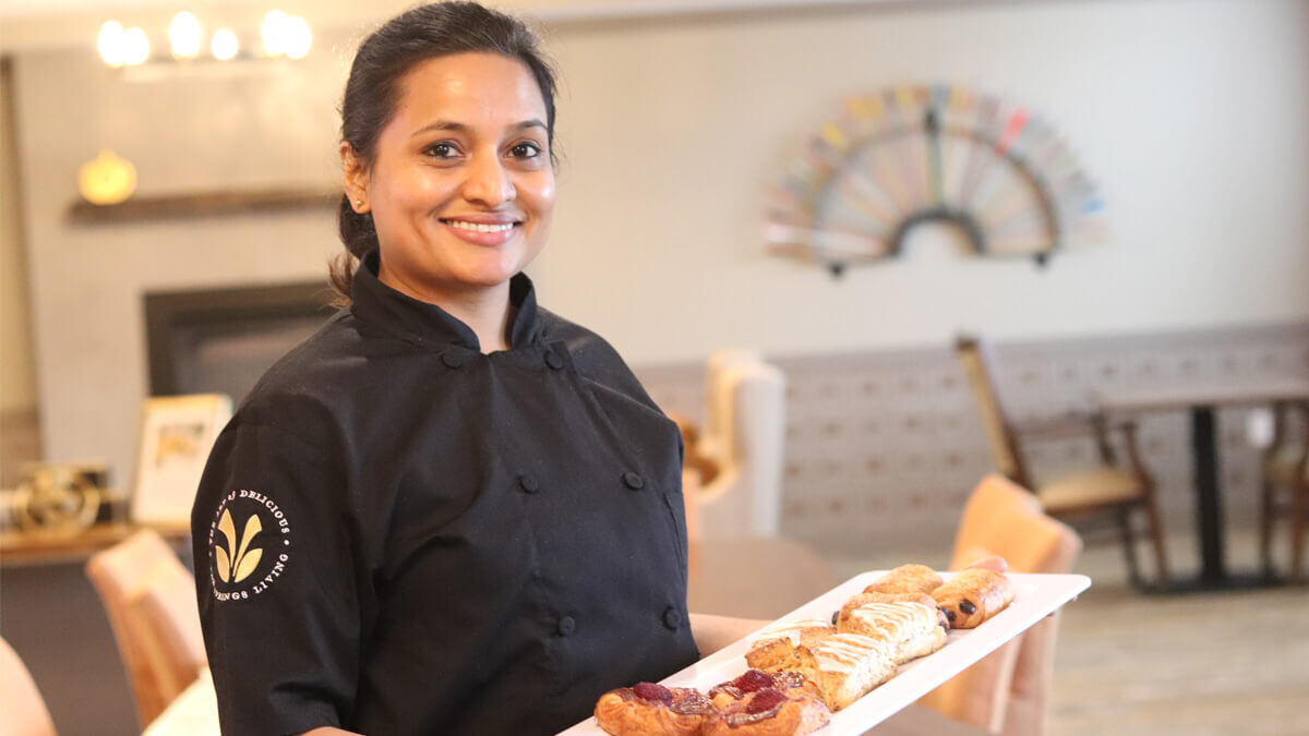 Staff member serving pastries in a dining area