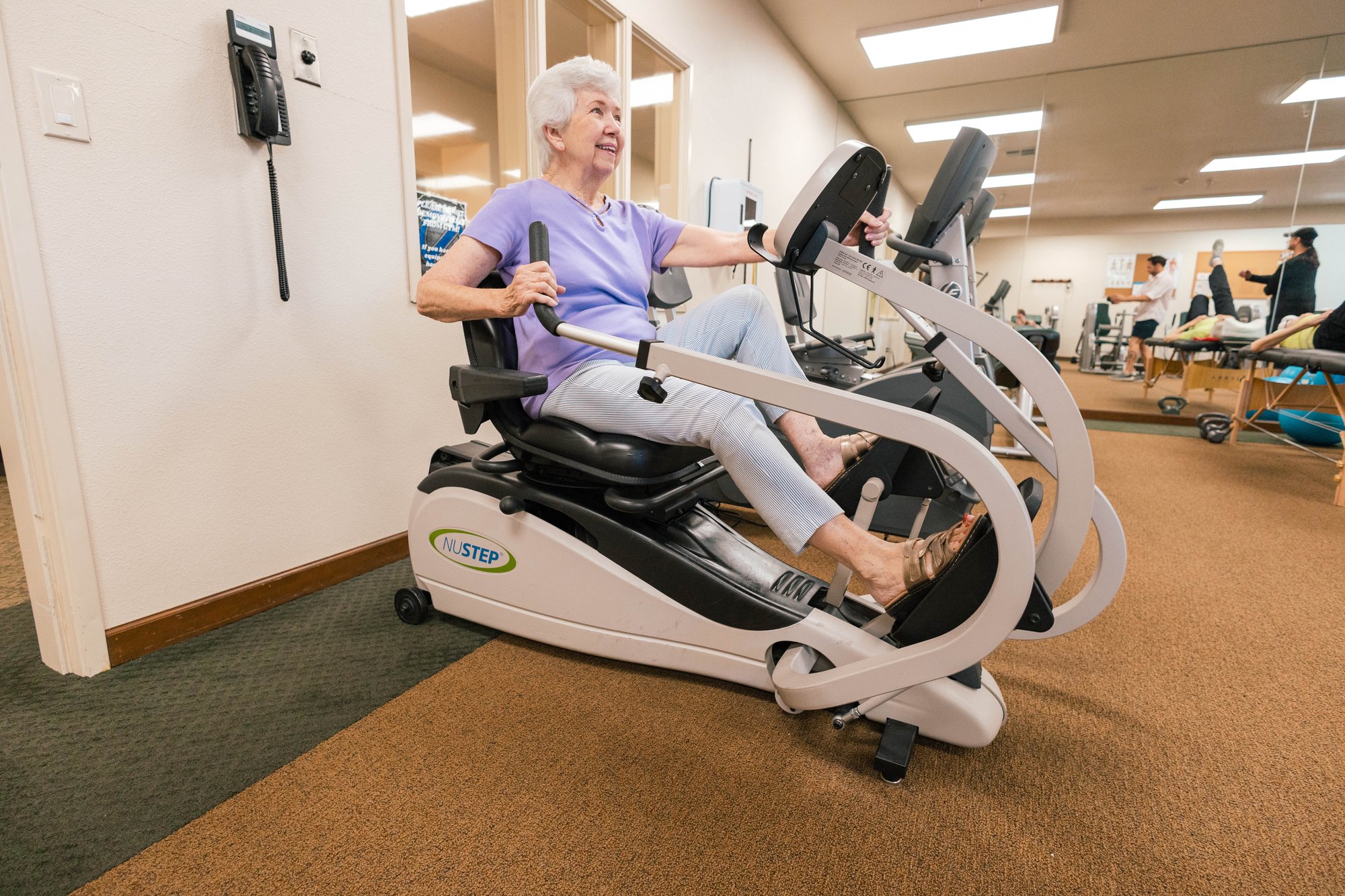 Resident exercising on a machine in a fitness area