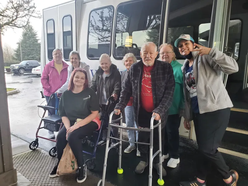 Residents and staff posing outside near a vehicle