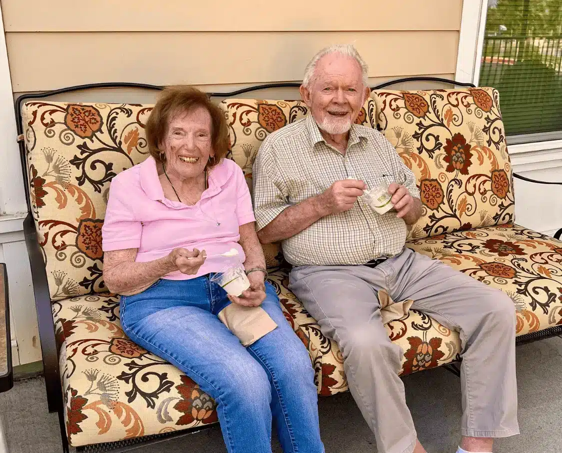Two residents enjoying ice cream on a porch sofa