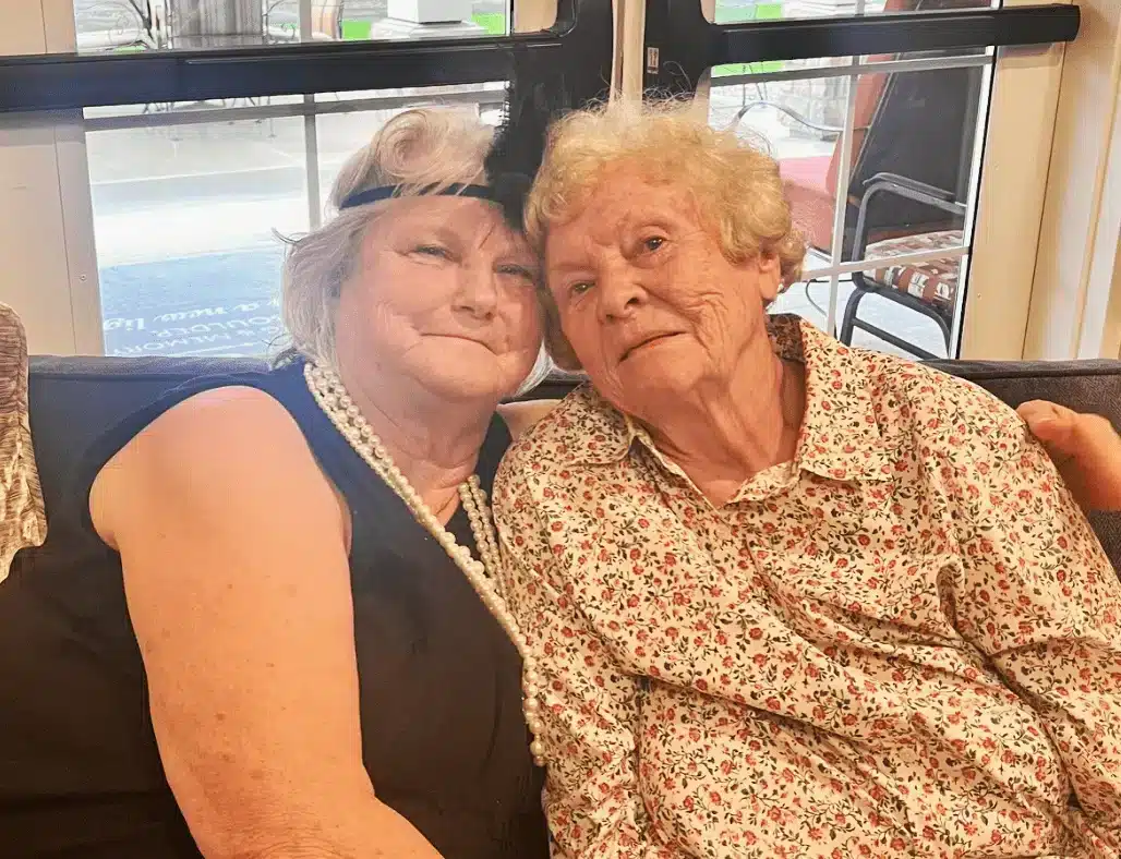 Two smiling residents sitting together on a couch