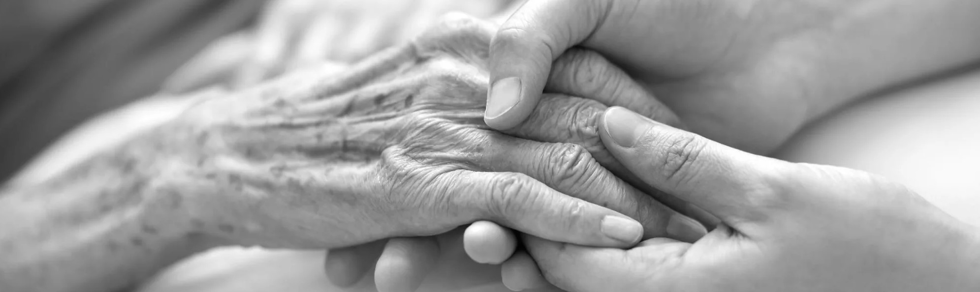 Close-up of a caregiver holding an elderly person's hand