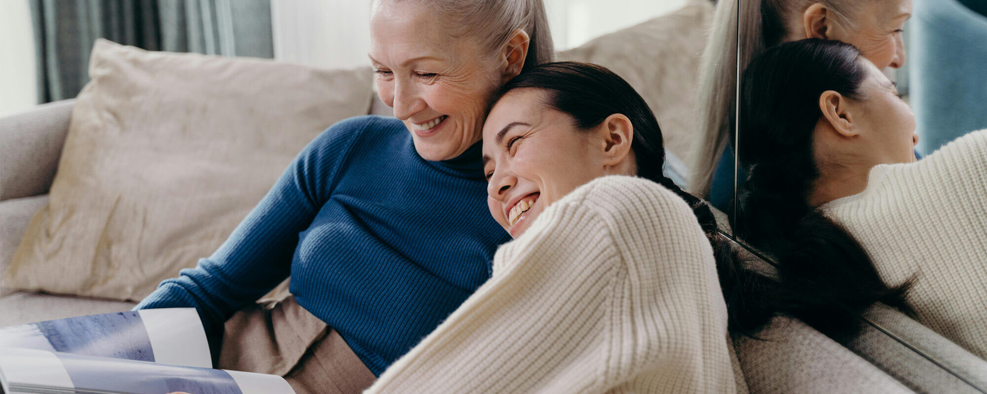 Two women sharing a joyful moment on a couch