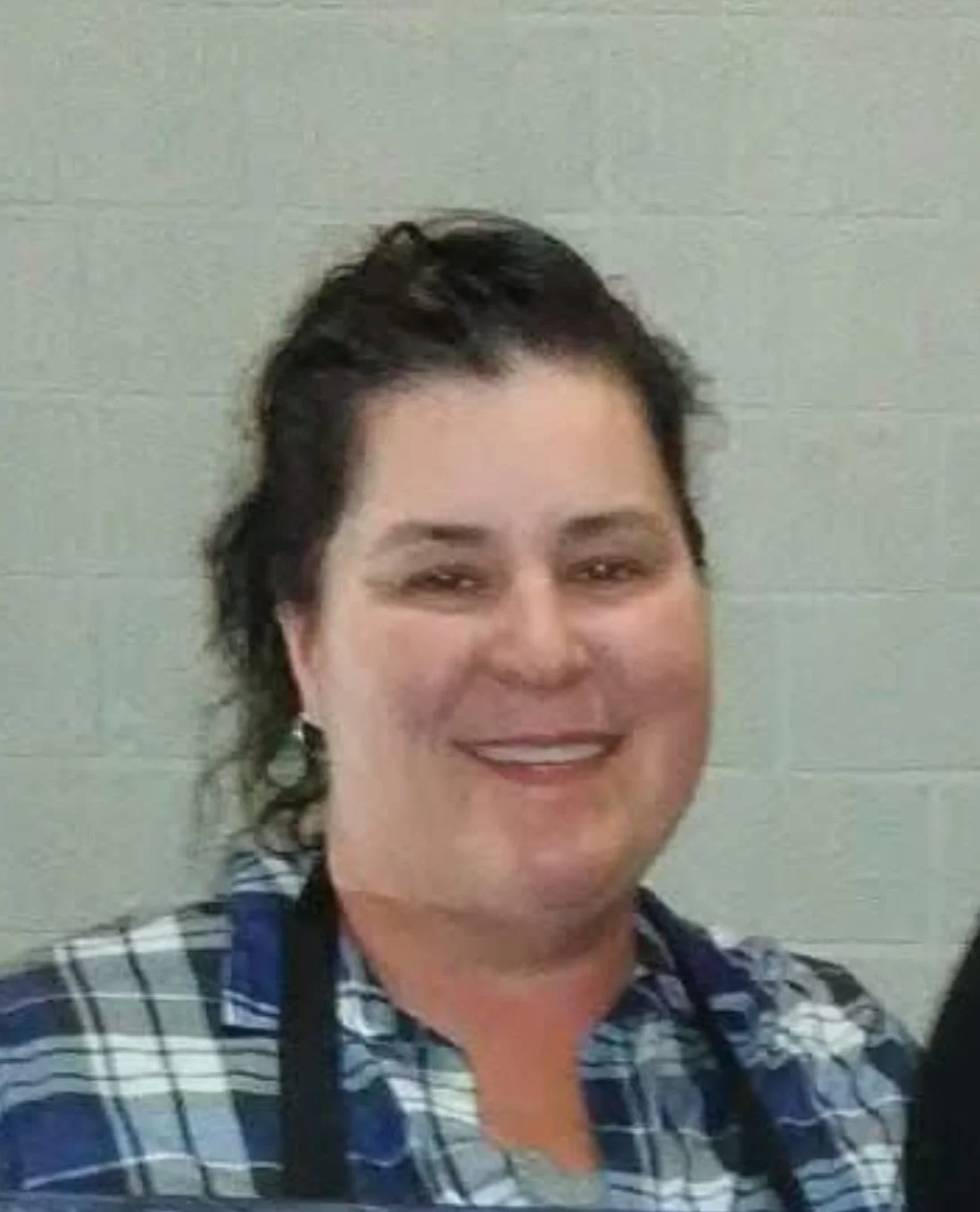 Smiling staff member in a plaid shirt