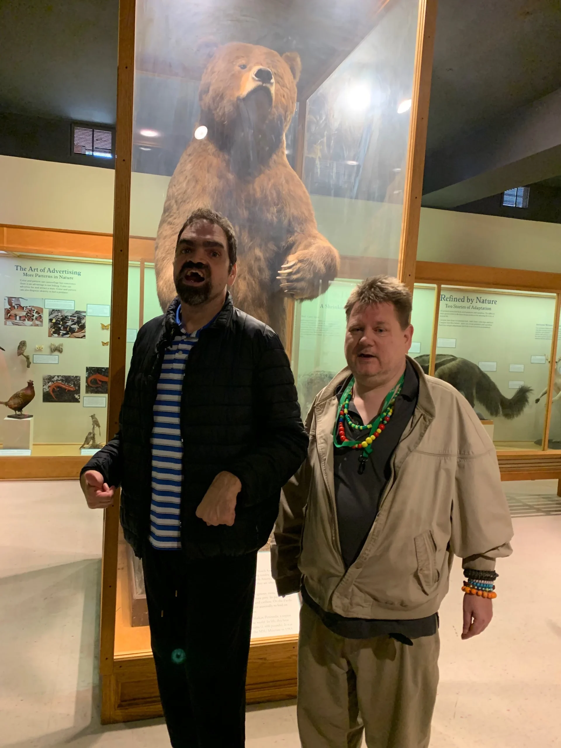 Two residents pose in front of a bear display.