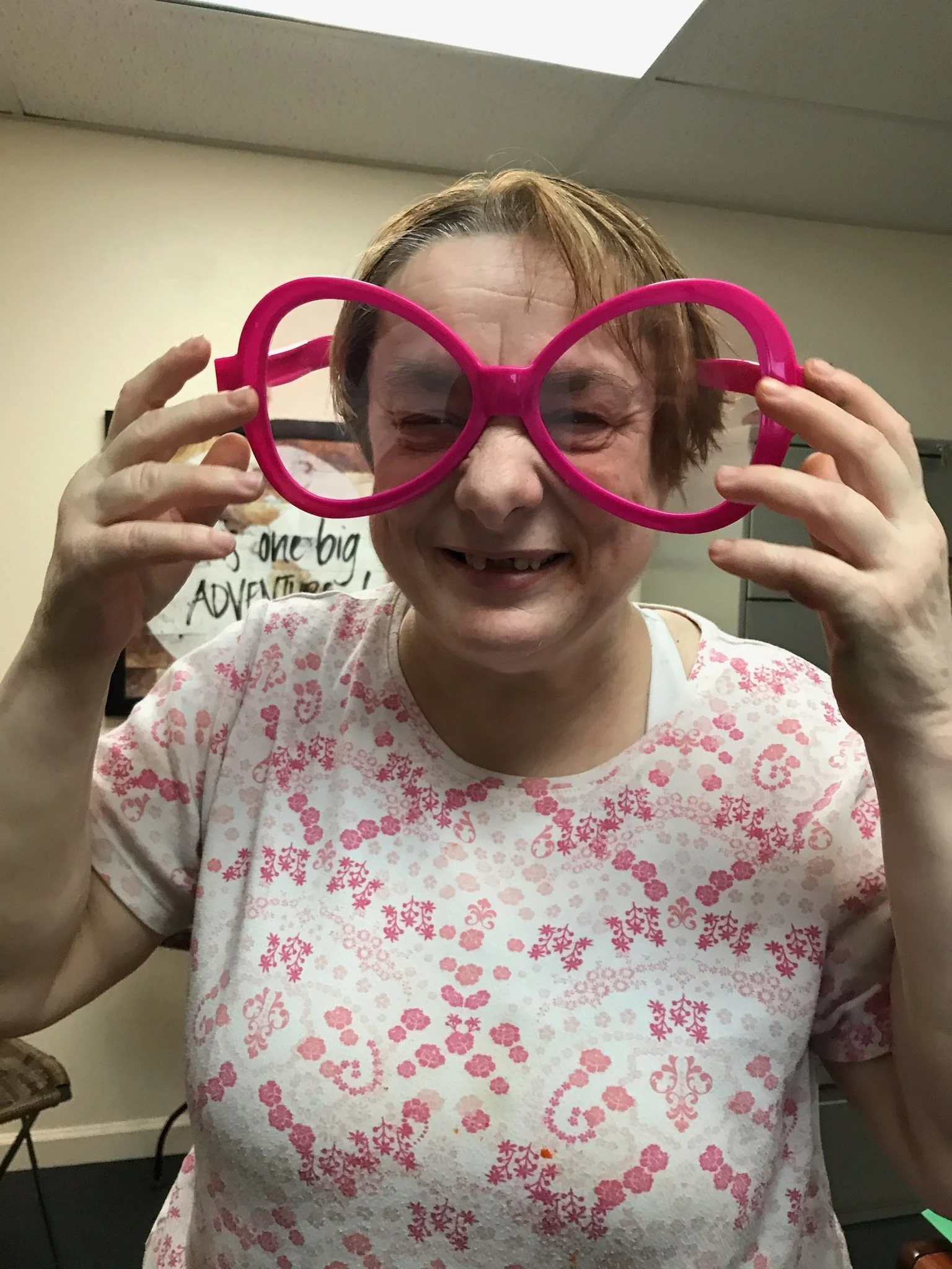 Resident wearing oversized pink glasses and smiling.