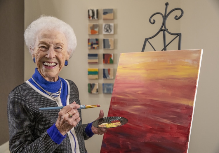 Elderly woman painting on canvas