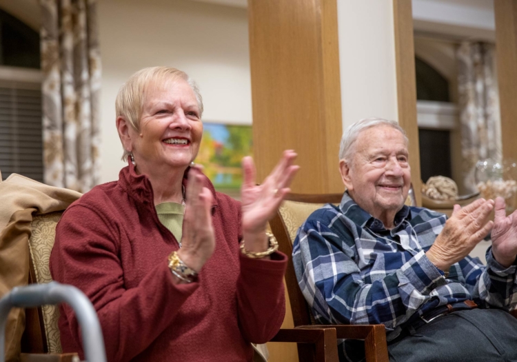 Two seniors smiling and applauding together.