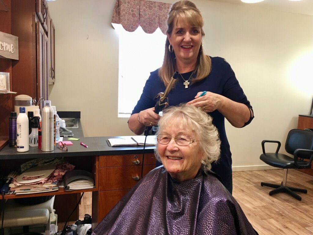 Resident receiving hair styling from staff.
