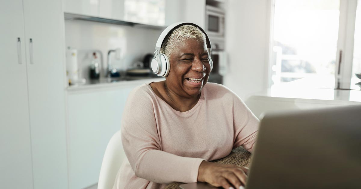Senior woman smiling while using a laptop