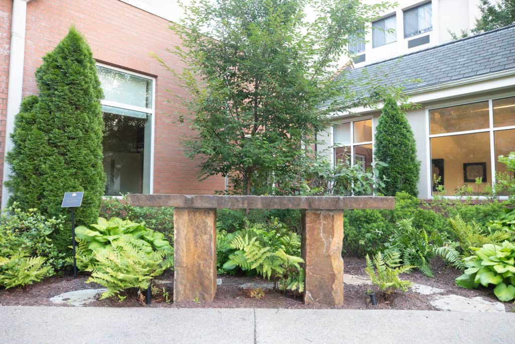 Outdoor garden area with stone bench and greenery.