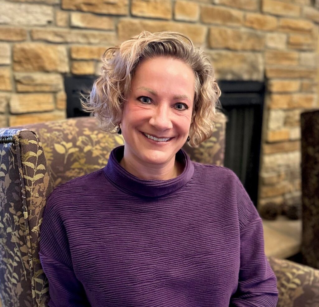 Staff member smiling in a cozy lounge area.