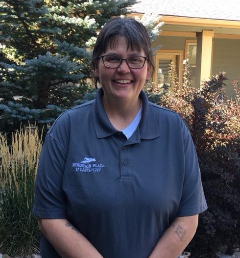 Staff member smiling in outdoor space with plants.