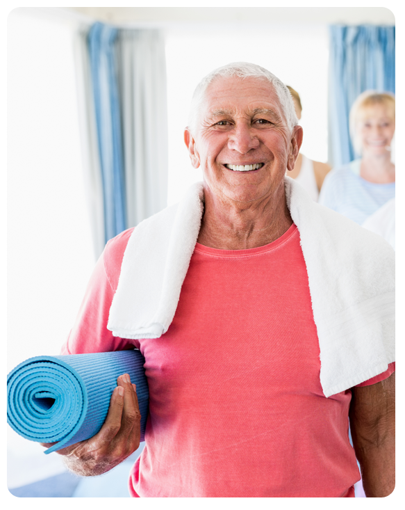 Senior man holding a yoga mat, smiling