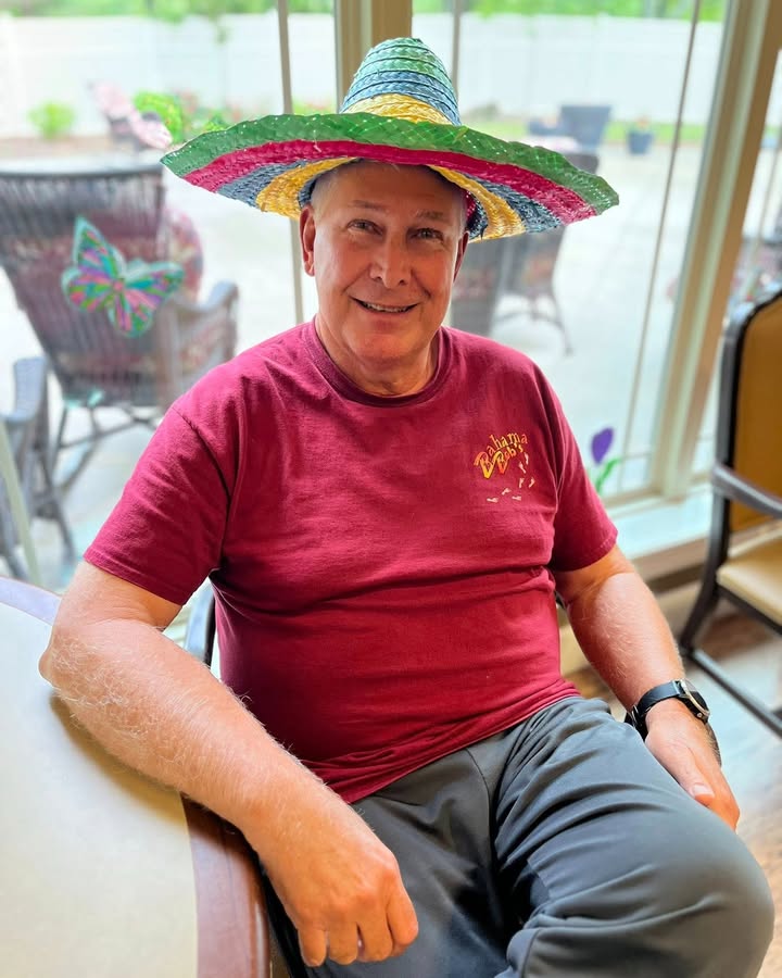 Resident wearing a festive hat, sitting in a common area.
