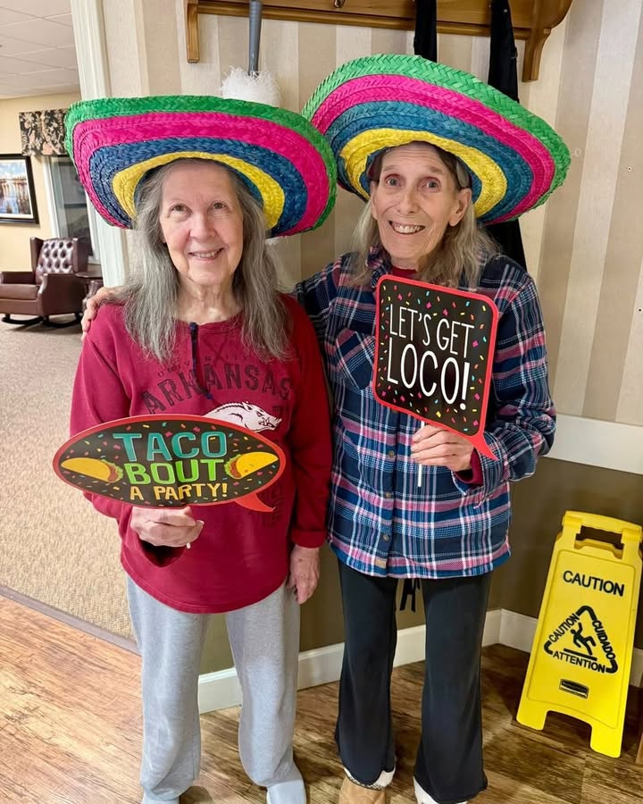 Two residents celebrating with hats and signs