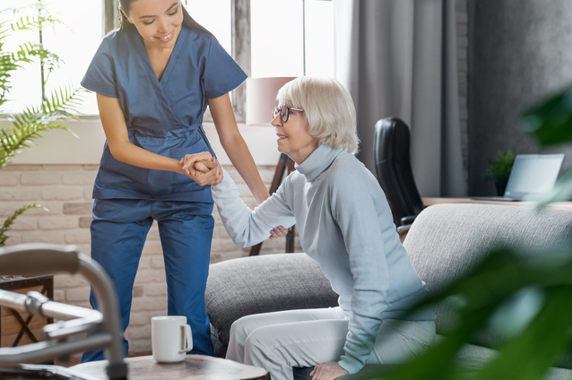 Caregiver assisting a senior in a cozy living room