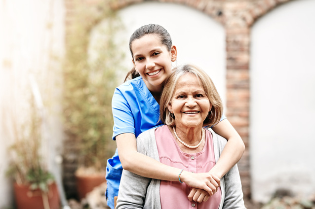 A caregiver with a senior resident outside.