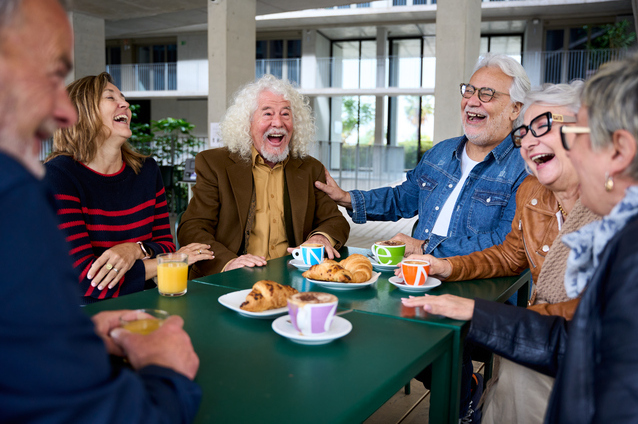 Seniors laughing and enjoying pastries at a table
