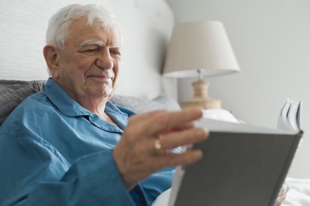 Senior man reading a book in bed