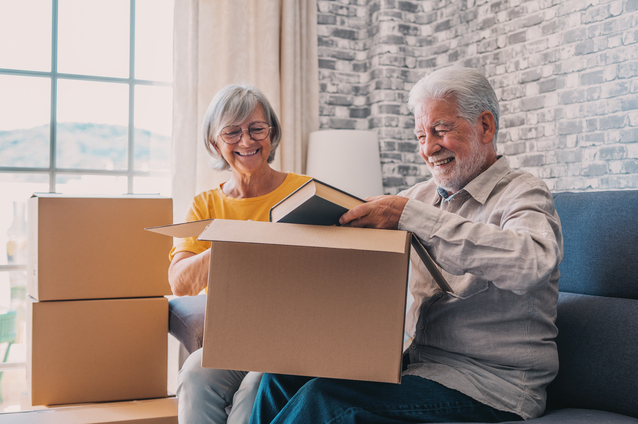 Two seniors unpacking boxes in a cozy living room.