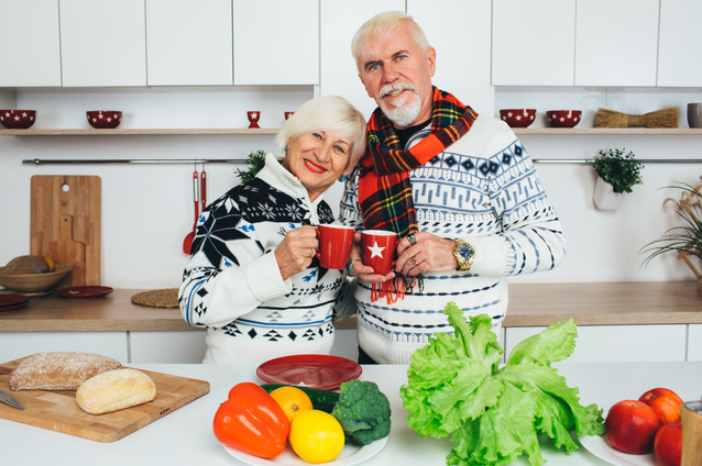 Elderly couple enjoying cooking together in a kitchen.