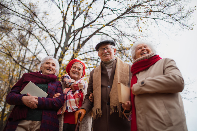 Four seniors smiling outdoors in autumn