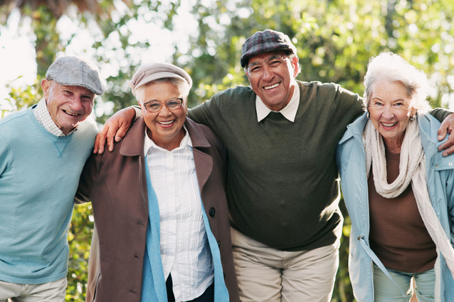 Group of smiling seniors in a garden setting.