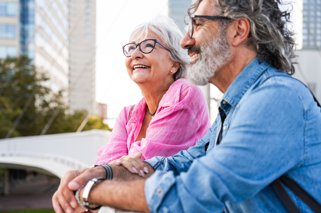 Two smiling seniors enjoying a conversation outdoors.